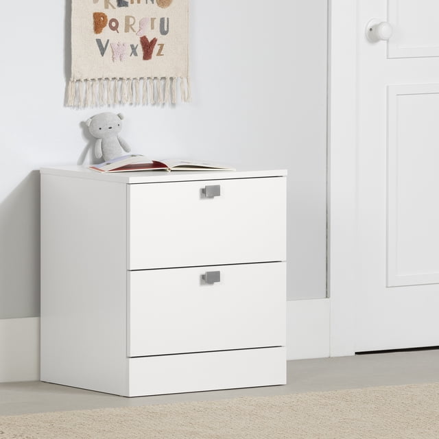 South Shore Spark 2-Drawer Nightstand for Child in pure white with two spacious drawers on metal runners and square metal handles, placed on a light floor against a white wall with a stuffed bear and an open book on top, ideal for organizing children's bedroom essentials and encouraging independence.