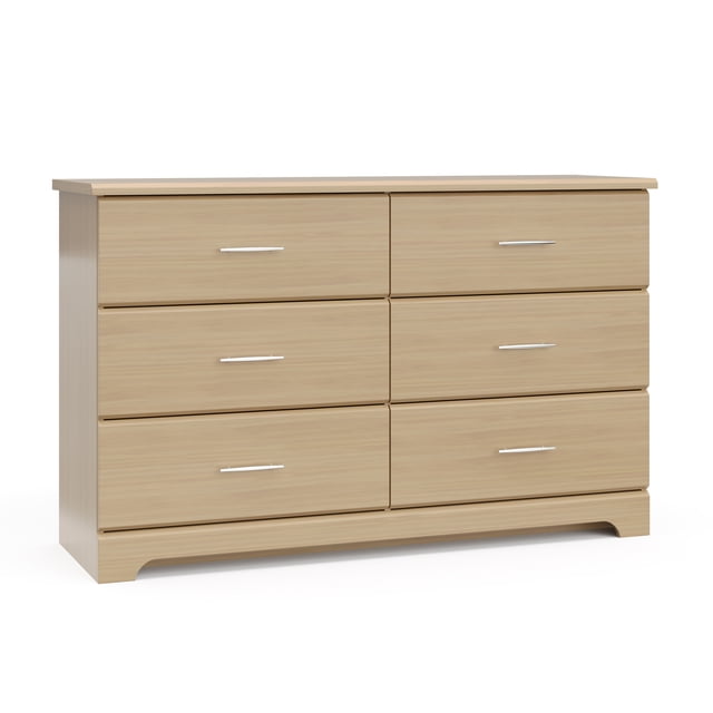 Storkcraft Brookside 6-Drawer Double Dresser in light wood laminate with six spacious drawers featuring euro-glide tracks and sleek metal handles, designed for kids' rooms and nurseries with a safety interlocking drawer system and tip-over restraint kit for secure storage.