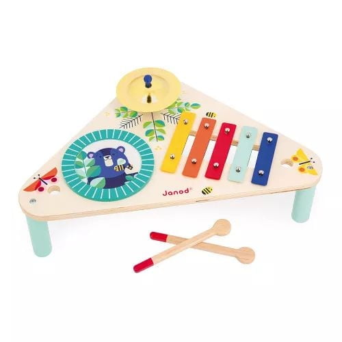 Janod wooden children's table with a triangular shape featuring a drum, yellow cymbal, and five-tone metal xylophone in vibrant colors, decorated with illustrations of a bear, bees, butterflies, and leaves, including two wooden drumsticks, suitable as a Montessori educational toy for musical stimulation.