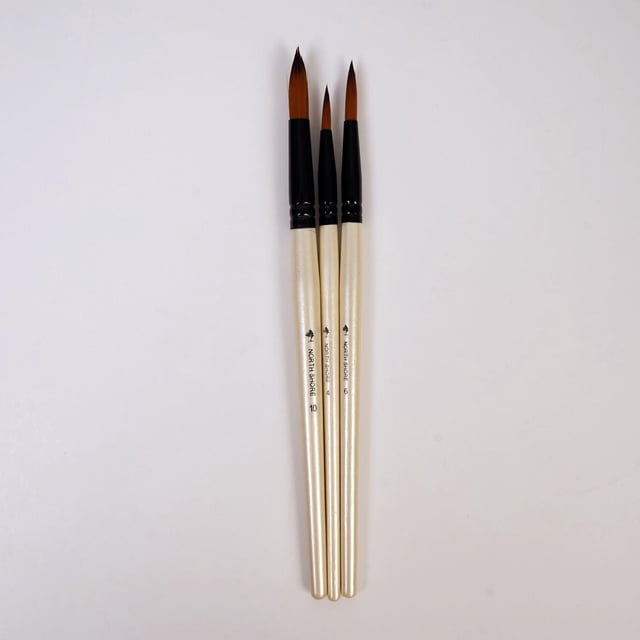 North Shore's 3 piece paint brush set includes three round tipped nylon firm brushes in sizes 4, 6, and 10 with cream-colored wooden handles and black ferrules, designed for oil and acrylic paint, displayed on a white background.