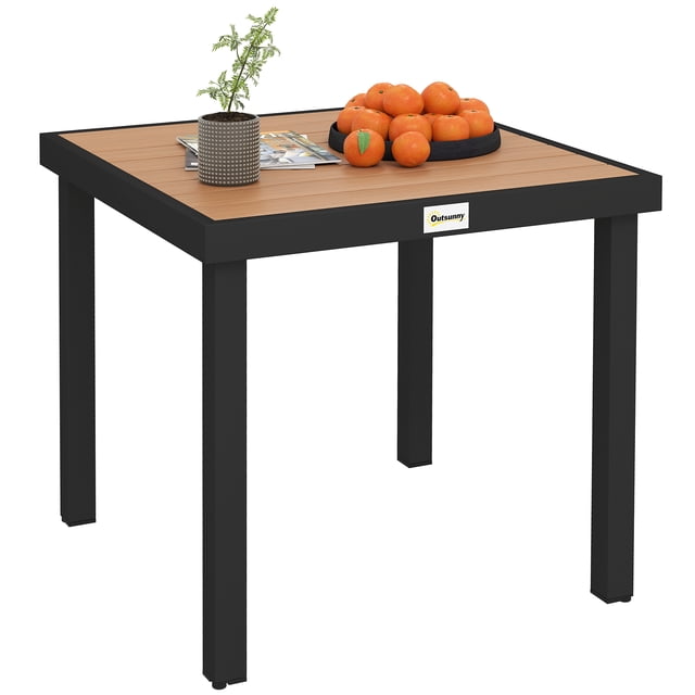 Outsunny Table à Manger d'Extérieur pour 4, Table de patio Carrée avec Dessus en Plastique Imitation Bois Naturel et Pattes en Aluminium Noir Durables. Comprend des Patins de Pieds Ajustables Antidérapants pour la Stabilité et Est Résistante aux Intempéries et Facile à Nettoyer. Idéale pour les patios, les Vérandas Ou le Bord de la Piscine. Exposée avec des oranges, une Plante et des magazines sur le Dessus de Table.
