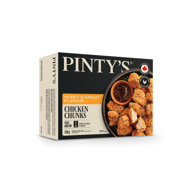 Pintys Honey & Garlic Flavoured Chicken Breast Chunks, Seasoned, Breaded, Uncooked in a black and beige box featuring a plate of golden breaded chicken chunks with a small bowl of honey garlic dipping sauce, made with Canadian chicken, 730 g package ideal for frozen appetizers and snacks.
