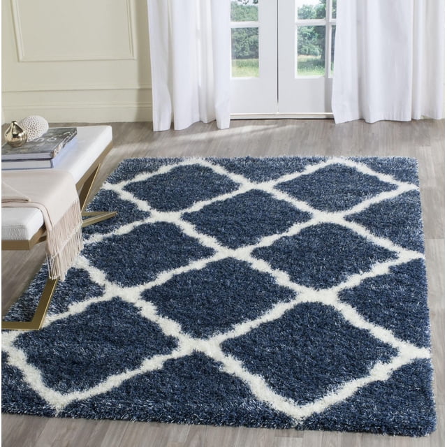 Safavieh Montreal Tapis Shag Géométrique Cebrail avec une Peluche à Poils Longs Bleu Foncé et un Motif Géométrique à Losanges Blancs, Posé sur un Plancher de Bois Clair dans une Pièce Éclatante avec des Rideaux Blancs et un Banc Moderne, Convient aux Intérieurs Contemporains Ou Transitionnels.