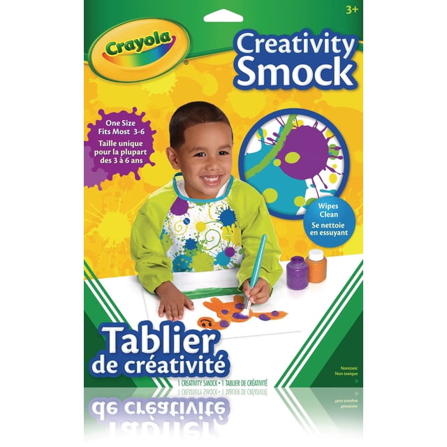 Crayola Smock de Créativité Porté par un Enfant, avec de Longues Manches Vertes et un Panneau avant Blanc Décoré de Éclaboussures de Peinture Bleues, Violettes et Jaunes. l'Enfant Peint une Figurine Colorée sur du Papier Blanc avec un Pinceau, avec des Bouteilles de Peinture Violettes et orange à Proximité. le Smock Est Essuyable, Ajustable et Conçu pour les Enfants de 3 à 6 Ans. l'Emballage Comprend un Texte Bilingue Anglais et Français.