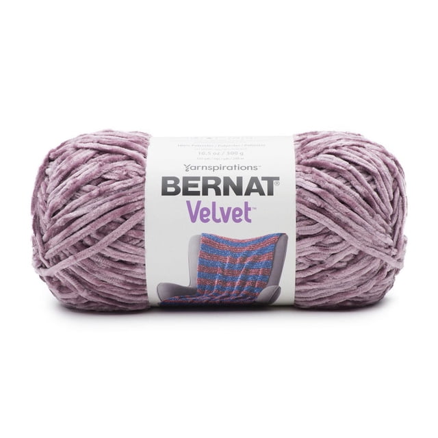 Bernat® Velvet™ Yarn, Polyester #5 Bulky, 10.5oz/300g, 315 Yards in dusty mauve, shown as a skein with a white label featuring the Bernat logo and a photo of a knitted blanket on a chair, highlighting its soft, velvety texture ideal for bulky knitting and crochet projects, recommended for hand washing to maintain quality.