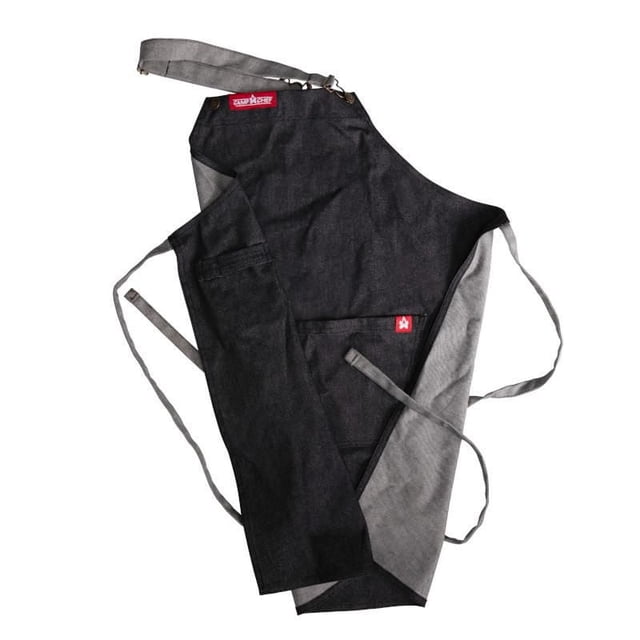 Camp Chef's Apron in black and grey 100% cotton canvas with water-resistant finish, adjustable neck strap and waist ties, reinforced bib buckle loops, two large front pockets, knee-length for full coverage, ideal for grilling and kitchen use, also suitable as a protective work apron.