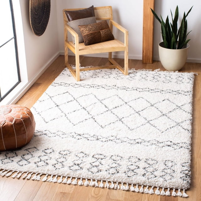 Safavieh Moroccan Fringe Tapis Shag Géométrique Scarlett pour Aire avec Fils Synthétiques Peluche Blancs et Motifs Géométriques Noirs en Losange et Tribaux, Bords à Franges, Exposé sur un Plancher de Bois Clair sous une Chaise en Bois avec Siège Tressé et Coussins Bruns, à Côté d'Une Plante Serpent en Pot et d'Un pouf en Cuir, Convient pour Améliorer le Confort et le style dans des Pièces Modernes Ou Campagnardes Chic.