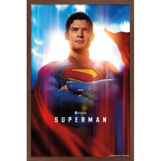 DC Studios Superman (2025) - Affiche Murale Gros Plan d'Une Feuille, 22,375 Pouces x 34 Pouces Encadrée, Montrant un Gros Plan Centré de Superman en Costume Texturé Bleu avec l'Emblème « s » Rouge et Jaune sur Sa Poitrine et Ses Bras Croisés. l'Arrière-plan Présente des Stries de Lumière Blanc Vif et Bleu avec une cape Rouge Fluide. l'Affiche Comprend le Texte « Regarde en l'Air », le logo DC Studios, et « Superman » au Bas.