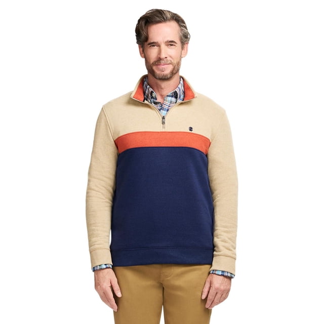 IZOD LS PERFRMNCE FLEECE COLORBLOCK¼ ZIP sweatshirt with a beige upper section, orange chest stripe, and navy blue lower section, worn over a blue plaid shirt and paired with khaki pants. It features a quarter-zip closure and IZOD 'IZ' logo embroidery on the left chest. Made from a soft cotton-polyester blend, this fleece is suitable for casual and business casual wear and often used for layering in cooler weather.