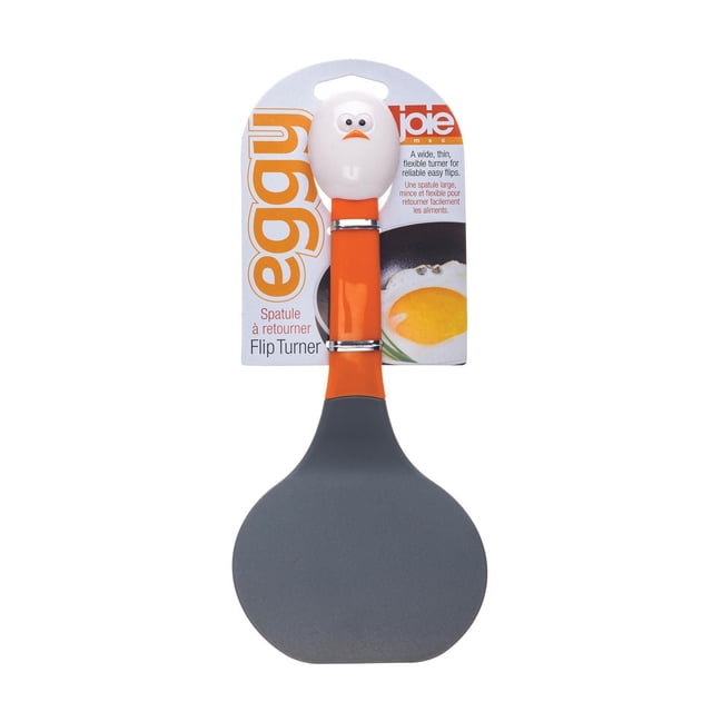 EGGY FLIP TURNER kitchen spatula with a wide, thin, flexible gray silicone head and an orange handle topped with a white egg-shaped grip featuring eyes and a beak, designed for easy flipping of food, shown in retail packaging with a fried egg image and bilingual text.