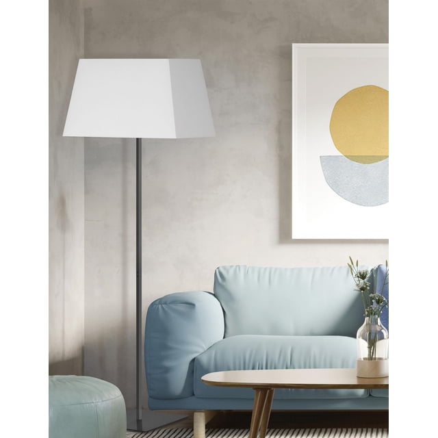Gretchen 1 Light Square Floor Lamp with matte black metal base and white fabric square shade standing beside a light blue sofa in a modern living room with textured beige walls and abstract framed art, ideal for office or bedroom use.