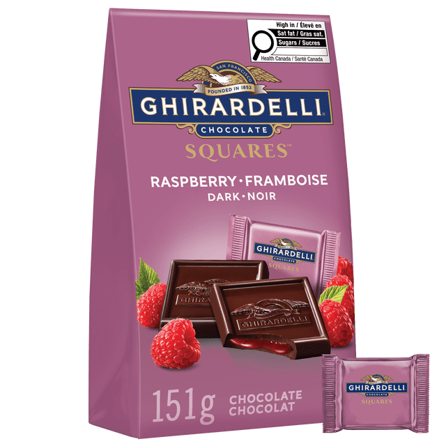 GHIRARDELLI Dark Chocolate Raspberry Squares Bag, 151g, with a purple bag featuring the Ghirardelli logo and gold lettering. The front shows two dark chocolate squares embossed with the Ghirardelli eagle, one bitten to reveal smooth raspberry filling, surrounded by fresh raspberries and a wrapped square. The bag includes a Health Canada label for high saturated fat and sugars. These individually wrapped squares are suitable for sharing or savoring.