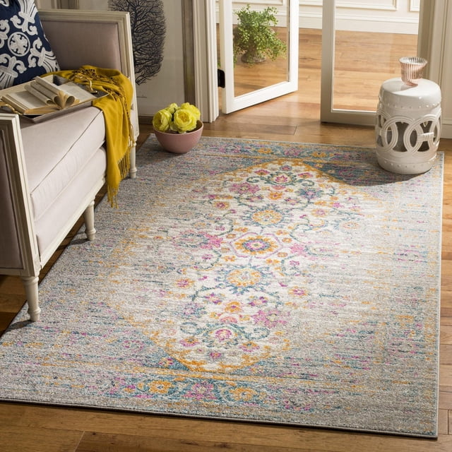 SAFAVIEH Madison Gabriel Tapis Traditionnel avec un Motif central de Médaillon floral en Rose, Jaune, Bleu et Gris Atténué sur Mélange de Polypropylène Gris Pâle, Posé sur Plancher de Bois Franc à Côté d'Un sofa beige avec un Jeté Jaune et un Livre Ouvert, Près d'Un Tabouret de Jardin en Céramique Blanc et d'Un Bol Rose avec des Fleurs Jaunes dans une Pièce Éclairée par le Soleil, Idéal pour Ajouter une Touche Stylée à la Déco Contemporaine de la Maison.
