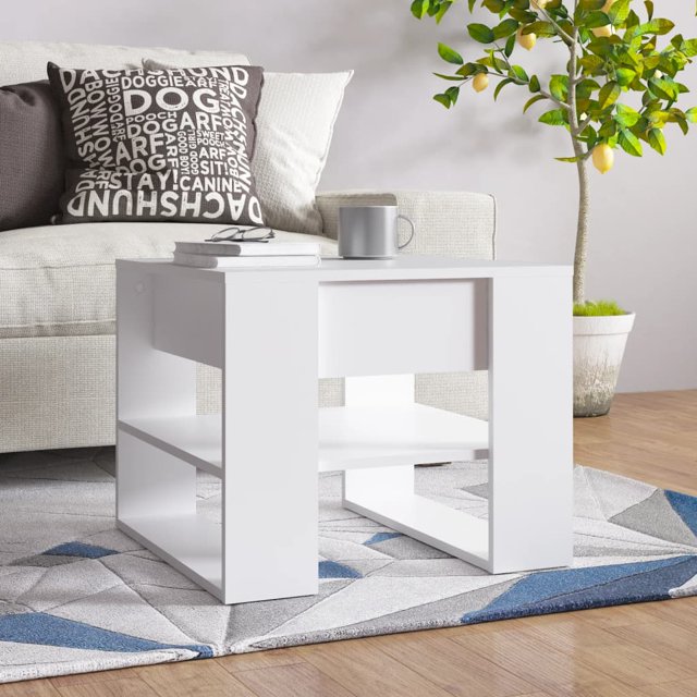 vidaXL Coffee Table White 55.5x55x45 cm made of engineered wood, featuring a modern square design with a smooth white finish. The table includes a practical tabletop for snacks, drinks, or decorative items, and a lower storage shelf for books or small essentials. Displayed in a cozy living room setting with a grey sofa, decorative pillows, and a potted plant in the background.