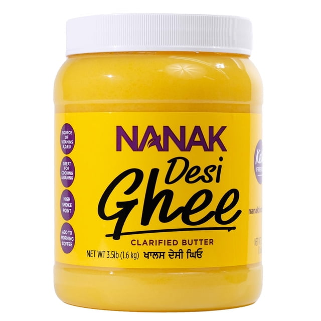 Nanak Pure Desi Ghee – Clarified Butter, 1.6KG, a clear plastic jar with a white screw lid filled with yellow clarified butter, featuring a yellow label with purple and black text highlighting its high smoke point and rich source of fat-soluble vitamins A, D, E, and K, suitable for cooking, baking, and adding to morning coffee.
