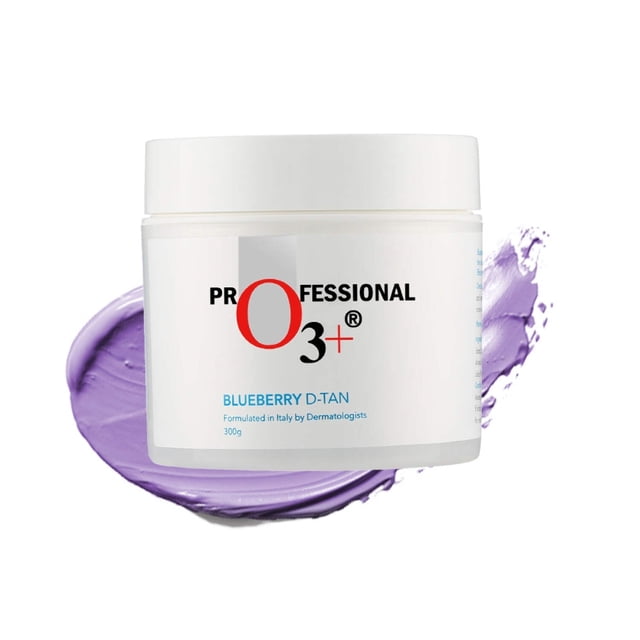O3+ Blueberry Dtan Tan Removal for Face Body - 300 gms. A white jar with a clean design featuring the O3+ logo and product name. The jar is placed against a background with a smear of purple cream, highlighting the product's texture. Designed for effective tan removal and skin brightening for both face and body, formulated with natural ingredients like camphor and eucalyptus.