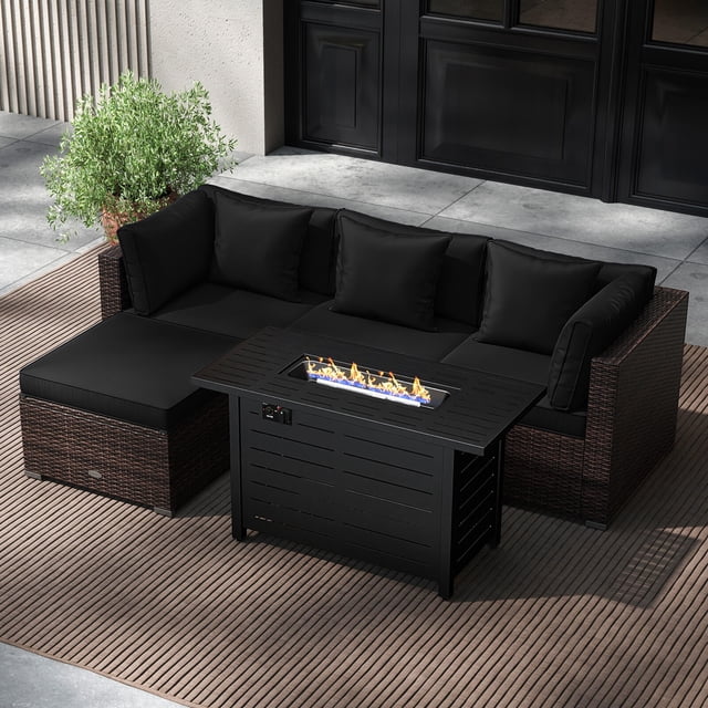 Costway 5 PCS Patio Furniture Set with heavy-duty frame and premium PE rattan construction. Includes black cushioned corner sofas, an armless chair, an ottoman, and a 60,000 BTU firepit table with a metal top. The firepit table doubles as a coffee table with a lid. Perfect for outdoor conversation and relaxation, displayed on a patio with a striped outdoor rug and greenery in the background.