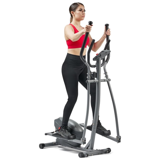 Sunny Health & Fitness Performance Compact Elliptical Machine with 8-Level Adjustable Resistance, Pulse Sensor, and Bluetooth-enabled SunnyFit App shown in a front 3/4 view with a person exercising. The elliptical features a grey steel frame, dual pulse-sensor handlebars, textured footplates, a large LCD display, and a device holder. It offers smooth magnetic resistance with a 28cm stride length and built-in wheels for easy transport, ideal for indoor cardio workouts.