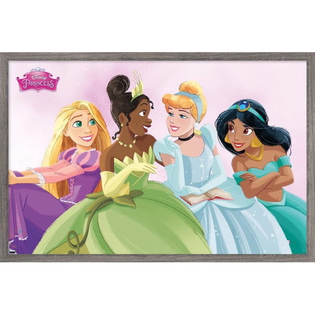 Disney Ultimate Princess Celebration - Group Wall Poster, 22.375" x 34" framed featuring four Disney princesses in vibrant gowns on a pink background. Includes a princess in a purple dress with long blonde hair, a princess in a green gown with yellow gloves and a crown, a princess in a sparkling light blue dress holding an open book, and a princess in a turquoise outfit with gold jewelry. The satin-finish framed poster is lightweight and easy to hang, suitable for bedroom or party décor.