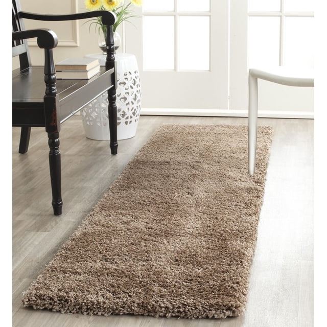 Safavieh Milan Harlow Tapis Shag Uni avec un Poil Shag Rectangulaire taupe en Fils Synthétiques Durables, Tissé Mécaniquement pour un Entretien Facile, Posé sur un Plancher de Bois Clair entre une Chaise en Bois Noire et une Chaise Blanche Près d'Un Tabouret de Jardin en Céramique Blanc avec des Fleurs Jaunes, Illuminé par la Lumière Naturelle d'Une Porte Vitrée, Convient pour Ajouter Chaleur et texture au décor Contemporain de la Maison.