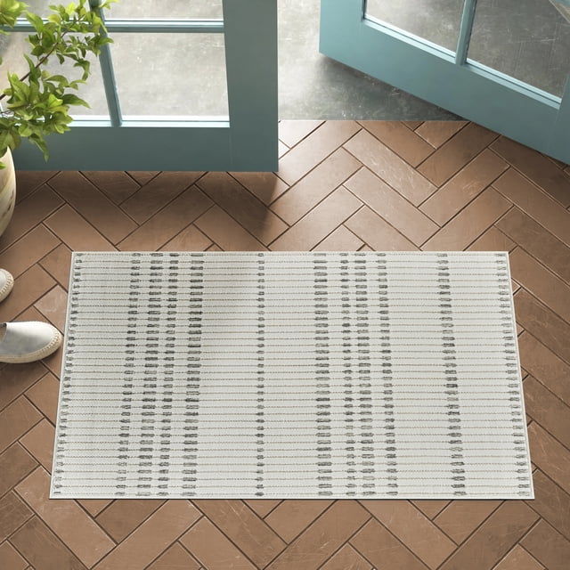 Rug Branch Maise Abstract Indoor Outdoor Area Rug in cream beige with a modern abstract striped pattern, sized 2'7" x 4'11", placed on brown herringbone tile floor near open blue doors and a potted plant, suitable for entryway, hallway, kitchen, or bathroom use.