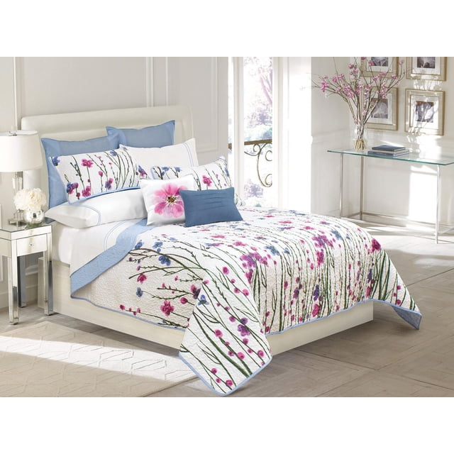 Safdie & Co. Home Deluxe Collection Ensemble de Courtepointe Multicolore 100 % Polyester sur Lit Très Grand avec Tête de Lit Rembourrée Blanche dans une Pièce Lumineuse. la Courtepointe et les Taies d'Oreiller Présentent une base Blanche avec des Imprimés Floraux Rose, Violet et Bleu et des Tiges Vertes, Bordées de Bleu Pâle. Comprend Deux Oreillers Bleus Unis et un Coussin Décoratif avec une Grande Fleur Rose. la Pièce a un Plancher de Bois Clair, une table de Nuit Miroir avec une Lampe Blanche et des Fleurs, et une table console en Verre avec des Fleurs Roses et des Livres Près d'Une Grande Fenêtre.