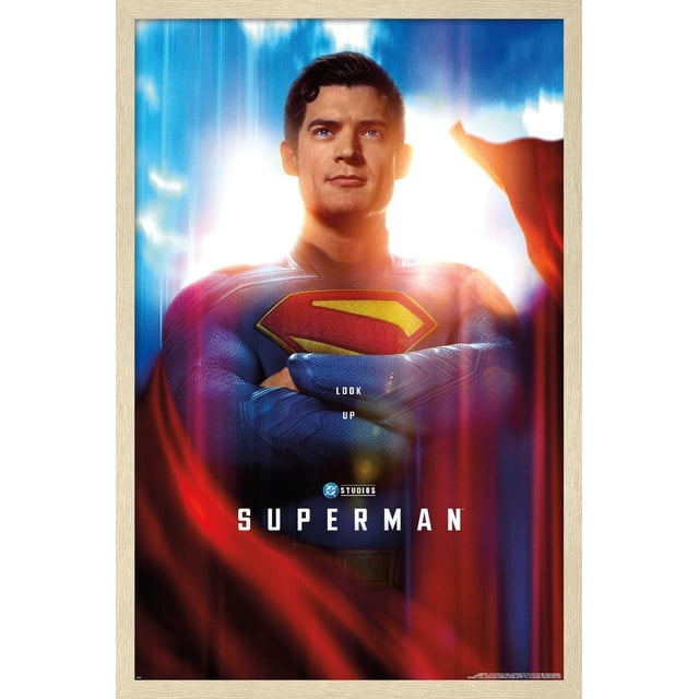 DC Studios Superman (2025) - Affiche Murale Gros Plan d'Une Feuille, 14,725 Pouces x 22,375 Pouces Encadrée, Montrant un Gros Plan Centré de Superman en Costume Texturé Bleu avec l'Emblème « s » Rouge et Jaune sur Sa Poitrine et Ses Bras Croisés. l'Arrière-plan Présente une Lumière Vive avec des Stries Bleues Verticales et une cape Rouge Fluide. le Texte sur l'Affiche Lit « Regarde vers le Haut » au-Dessus du logo DC Studios et « Superman