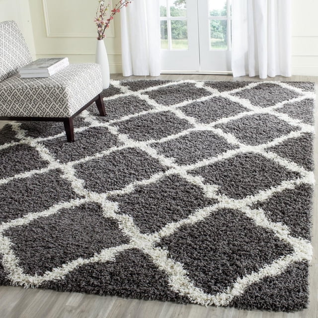 Safavieh Dallas Logan Geometric Shag Area Rug in dark grey with ivory Moroccan tile pattern, power-loomed polypropylene with a 2-inch plush pile, displayed in a bright room with light wood flooring and a patterned accent chair, ideal for adding contemporary style and comfort.