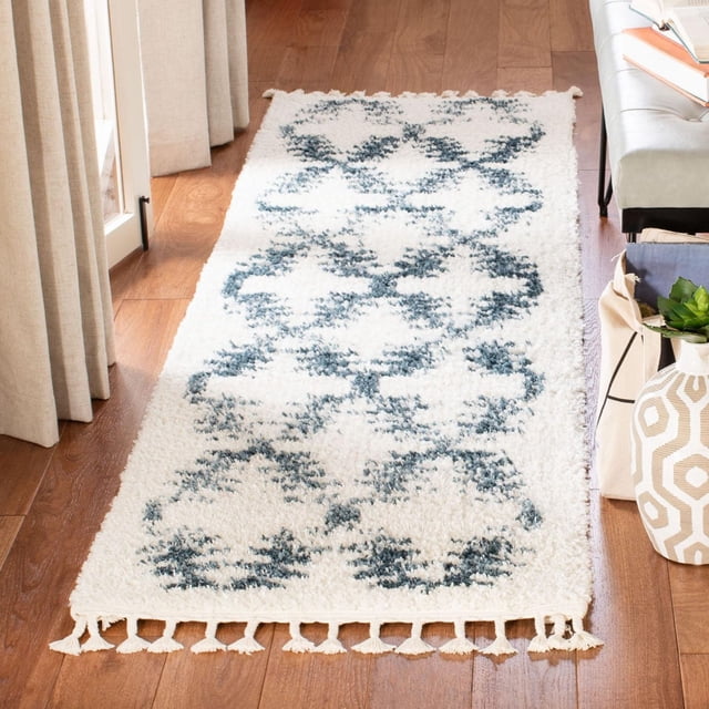 Safavieh Berber Fringe Seamus Diamond Shag Area Rug runner with 1.25-inch plush pile, white base and blue diamond tribal pattern, fringed edges, placed on hardwood floor beside sofa and curtains, suitable for adding bohemian style to narrow hallways or entryways.