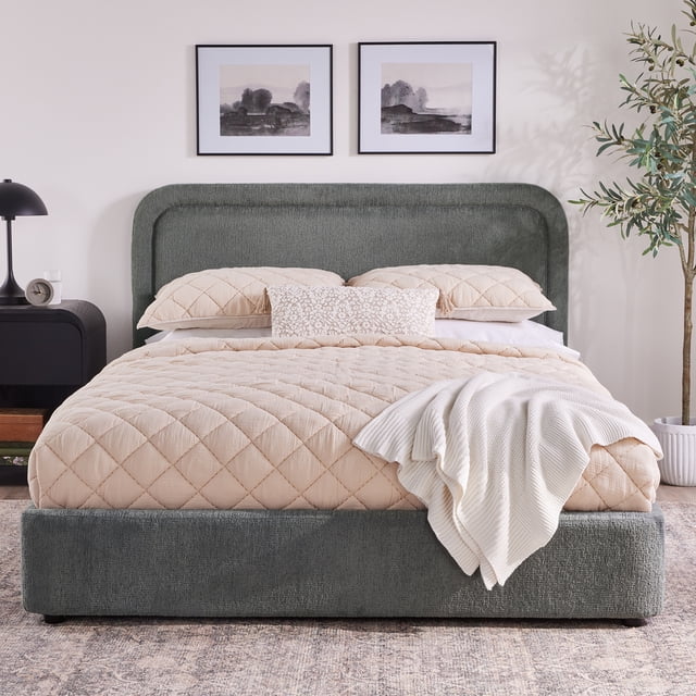 Better Homes & Gardens Juliet King Platform Bed in gray with a low-profile upholstered wood frame, rounded tufted headboard, and hidden feet creating a floating look, styled with beige quilted bedding and white throw, suitable for modern bedroom furniture.