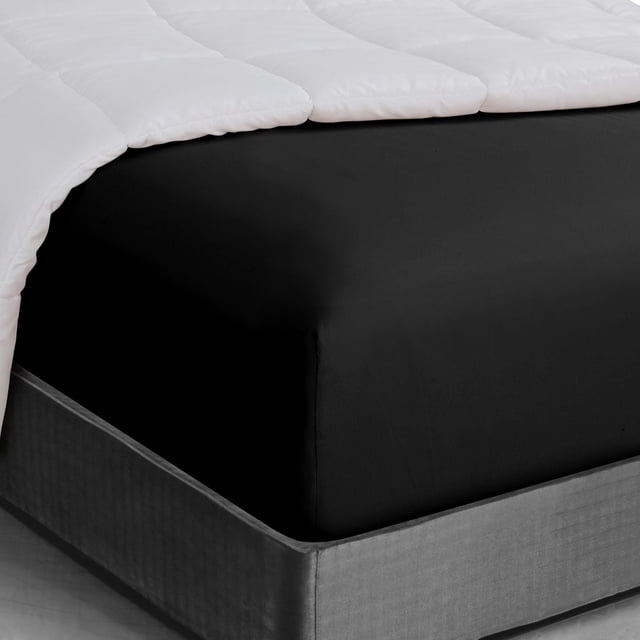 Basic fitted sheet in black with deep pockets snugly fitted on a mattress corner, shown in a close-up view with a white quilted comforter partially draped on top, made of wrinkle-resistant microfiber fabric ideal for easy care and machine washing, also suitable for replacing worn bedding pieces.