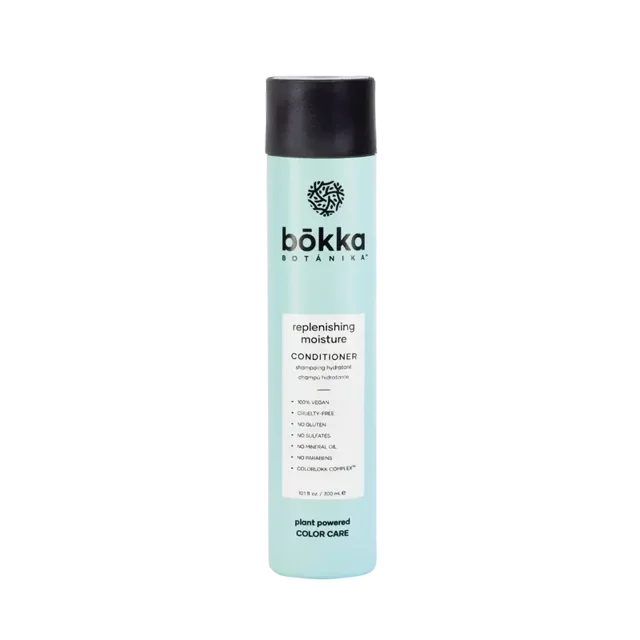 Bokka Botanika Replenish Revitalisant Hydratant dans une Bouteille de 10,1 Oz (300 ml). le Contenant Cylindrique Bleu Pâle Présente un Bouchon Noir et une Marque Audacieuse avec le Nom du Produit et des Avantages, Y Compris l'Hydratation, le Démêlage et la Nutrition pour les Cheveux Secs et Colorés. l'Étiquette Met en Valeur des Ingrédients Clés comme l'Abyssinie, l'Aloès et des Extraits de Noix de Kukui, Ainsi Que le Complexe COLORLOKK pour la protection