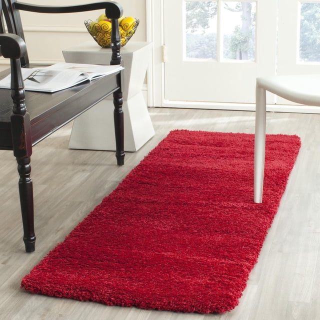 Safavieh Milan Harlow Solid Shag Area Rug in solid red with thick shag pile, rectangular on light wood flooring between a dark wooden bench and white chair near glass doors, suitable for adding warmth and texture to contemporary home interiors.