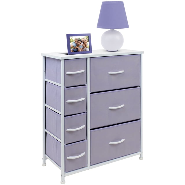 Commode à 7 Tiroirs - Violet avec Cadre en Acier et Dessus en Bois MDF, avec Sept Tiroirs en Tissu Violet pastel avec Poignées Blanches pour Organiser les Vêtements, les Jouets et les Articles Ménagers. la surface Supérieure Présente une Lampe Violette et un Cadre photo, Parfait pour la Déco Ou un Rangement Supplémentaire. Conception Légère et Compacte Idéale pour les Meubles pour Enfants dans les Chambres, les Salles de Jeux Ou les Garderies.