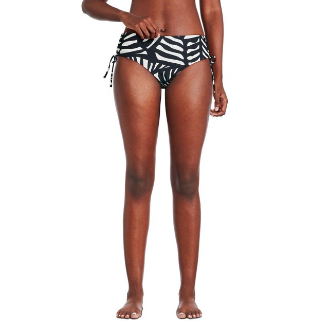 George Women's Bikini Bottom in black and white abstract leaf pattern, front view on a model. Made from soft tricot knit with elasticized waistband and legholes, featuring side ruching with adjustable ties for a flattering fit, suitable for swimming, lounging, or beach volleyball.