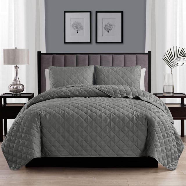 Swift Home ensemble de Courtepointe à Losanges Gris sur Lit Moderne avec Tête de Lit Rembourrée, Comprenant un Tissu polyester Matelassé à Losanges et des Couvre-Oreillers Assortis avec des Ourlets de 2 Pouces. Cet ensemble de Literie Lavable à la machine Est Présenté dans une Chambre Minimaliste avec des Tables de Nuit en Bois Foncé, une Lampe Argentée et des Imprimés Botaniques Encadrés sur un Mur Gris.