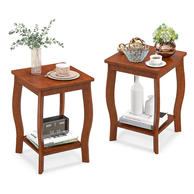 Gymax 2-Tier Square End Table Set of 2 Narrow Sofa Side Nightstand with Storage Shelf in walnut finish. Each table features a square tabletop and a bottom shelf for storage, supported by curved rubber wood legs. The compact design is ideal for small spaces, suitable as a nightstand, sofa side table, or display rack. The top surface is styled with decorative items, while the bottom shelf holds books and other essentials.