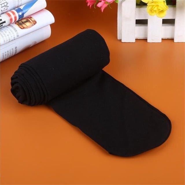 Bas Collants Opaques aux Couleurs Bonbon, Panty Mince pour Femmes, Noir, Fabriqué en Velours et spandex pour un Ajustement Confortable. Présente un Motif Opaque et un design à Pieds, Idéal à Agencer avec des Jupes, Robes, Bottes Ou Escarpins pour occasions Décontractées Ou Formelles. Présenté Roulé et Partiellement Déployé sur une surface orange Plate avec des Fleurs Décoratives et des magazines en Arrière-Plan.