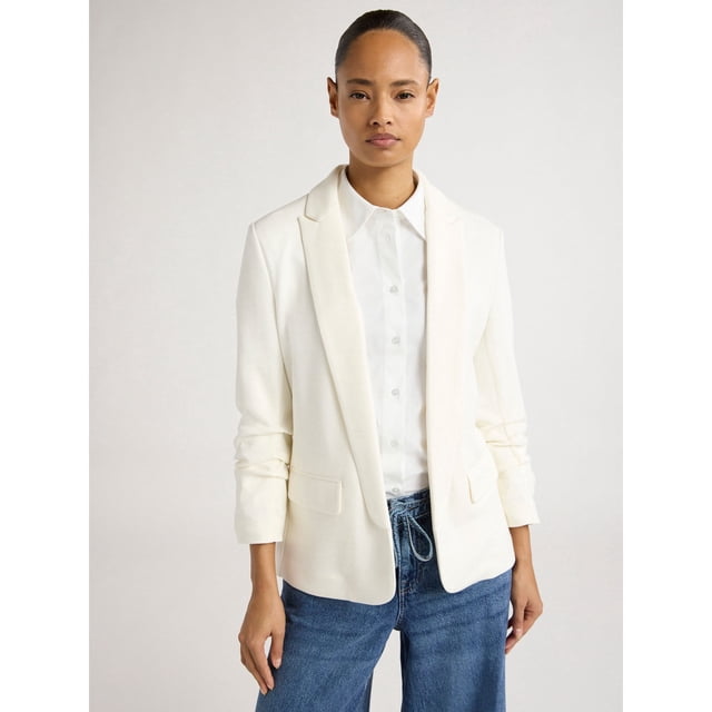 Scoop Women's and Women’s Plus Ultimate ScubaKnit Relaxed Blazer with Scrunch Sleeves in white, featuring a peak lapel, open front, and ¾-length scrunched sleeves. Made from ScubaKnit material with a relaxed fit, styled with a white button-up shirt and blue jeans. Includes two front flap pockets and decorative buttons at the cuffs.
