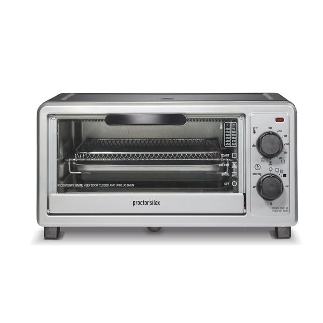 Proctor Silex Simply-Crisp™ Air Fryer Toaster Oven in silver with 4-slice capacity and 275 cu. in. interior, front-facing view showing mesh air fryer rack, bake pan, manual temperature and timer dials, and crumb tray, ideal for air frying, baking, broiling, and toasting on a countertop.