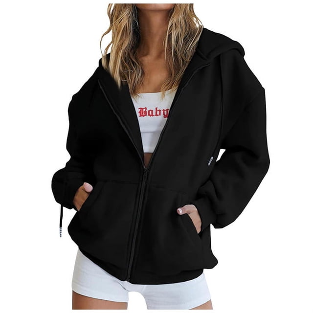 RKSTN Womens Zip Up Y2K Hoodies Long Sleeve Fall Oversized Casual Solid Color Sweatshirts Jacket with Pockets. A black oversized zip-up hoodie featuring long sleeves, kangaroo pockets, and a relaxed fit. Ideal for casual wear, fall fashion, and layering. The model pairs it with a white crop top and shorts for a trendy look.