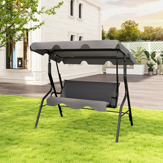 Gymax 3-Person Swing Chair Porch Swing Seat with adjustable canopy and removable cushion in gray. The swing features a sturdy A-shaped metal frame with anti-slip foot pads, a tilted backrest, and ergonomic armrests for comfort. The canopy is made of sun-proof and waterproof polyester fabric, providing shade and durability. Suitable for outdoor spaces like gardens, patios, and porches.