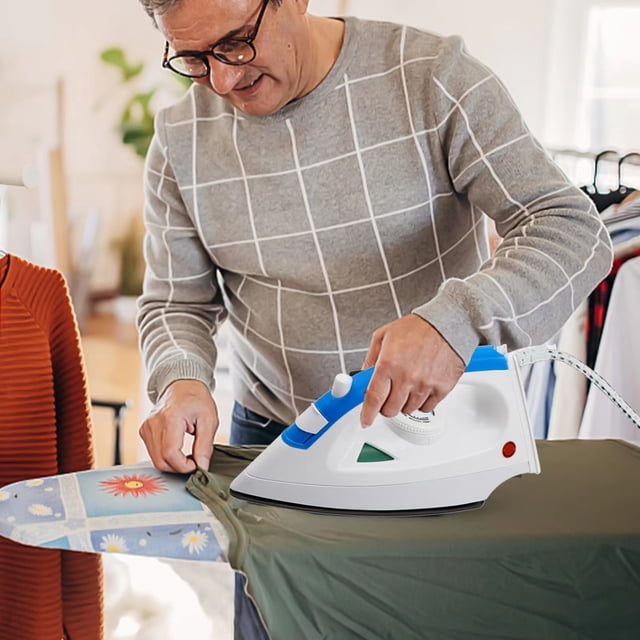 TopLLC Household Handheld Steam Electric Iron, a small portable iron with 1200W power and five-level temperature adjustment, shown in use on a green garment. The iron features a blue and white design, a nonstick soleplate, and a comfort grip handle. It is placed on an ironing board with a floral cover in a home setting.