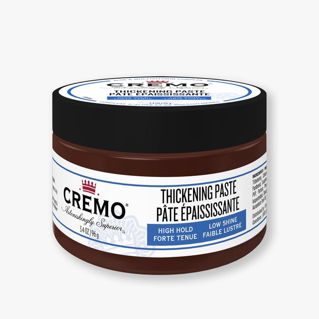 Cremo Hair Thickening Paste in a 3.4 oz (96 g) brown jar with black lid, labeled for high hold and low shine, designed to add texture and volume to short or fine hair with all-day hold and easy restyling.