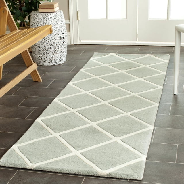 Safavieh Chatham Isaac Tapis à Losanges Géométriques en Laine Gris Pâle Tufté à la Main avec Motif de Losanges Blancs Surélevés et Poil Moyen, Posé sur un Plancher de Carreaux Foncés Près d'Un Banc en Bois et d'Un Tabouret en Céramique Blanc, Convient comme Tapis d'Accent Contemporain pour les Maisons Canadiennes.