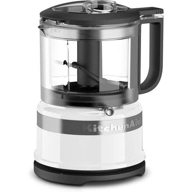 KitchenAid® 3.5 Cup Food Chopper with a clear 3.5 cup work bowl, black handle, and pour spout on a white base with silver band and KitchenAid logo. Includes a locking stainless steel blade and lid with drizzle basin for easy chopping, mixing, and pureeing of fresh ingredients.