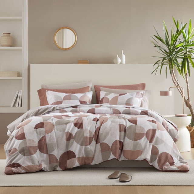 Regency Heights Full Size Comforter Set, 9-Piece Bed in a Bag Full, featuring a terracotta round geometric print. The set includes a comforter, standard sham, flat sheet, fitted sheet with side pockets, and two pillowcases. Made from soft, breathable microfiber, it is Oeko-Tex certified and machine washable. Displayed in a modern bedroom with neutral decor and a potted plant.