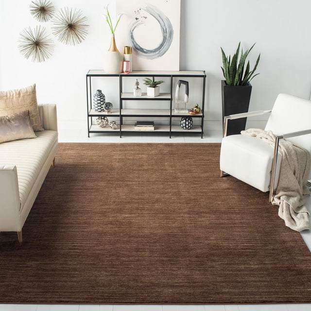 Safavieh Vision Adrasteia Tapis Uni Surteint dans des Tons Bruns Chauds avec une texture Subtile, Exposé dans un Salon Contemporain Comprenant un sofa Crème avec des Coussins Décoratifs, un Fauteuil Blanc avec un Jeté beige, des Étagères Métalliques Noires avec une Déco, et une Grande Plante Verte dans un Cache-Pot Noir, Idéal comme Tapis d'Accent pour les Espaces Intérieurs.