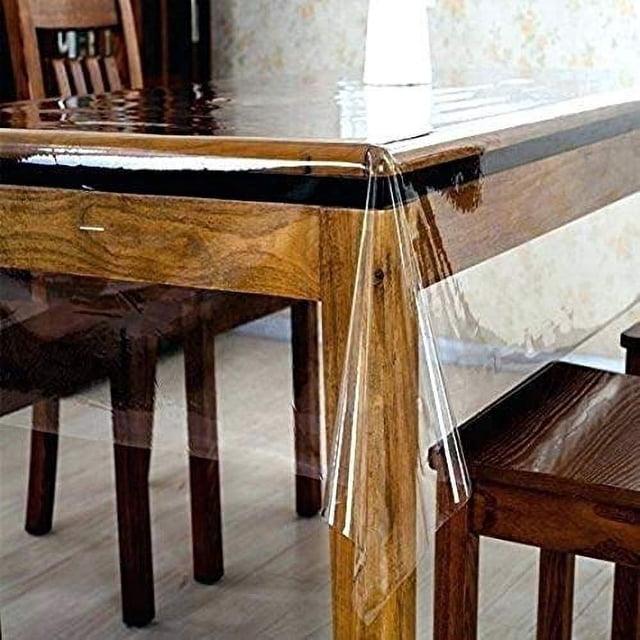Rooney Heavy-Duty 100% Vinyl Clear/Transparent Tablecloth TOP Cover, rectangular 60" x 102", displayed on a wooden dining table. The clear vinyl protector enhances the table's natural wood appearance while providing waterproof and stain-resistant protection. Suitable for safeguarding against spills, pets, and children. Easy to wipe clean with a damp cloth or sponge.
