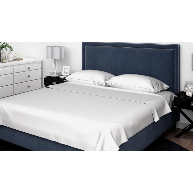 Johnson Home Ensemble de Draps 600 Fils - Draps 100 % Coton pour Lit Très Grand avec Tête de Lit Rembourrée Bleu Marine Bordée de Clous Argentés. les Draps et Taies d'Oreiller Gris Pâle Lisses et Respirants Offrent une Durabilité et un Confort en Coton de 600 Fils. la Chambre Moderne Présente une Commode Blanche avec Déco et une Lampe en Verre sur une Table de Nuit Noire.